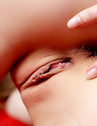 Stunning blonde teen Daisy A wears nothing but her red necklace as she poses erotically on the red couch.